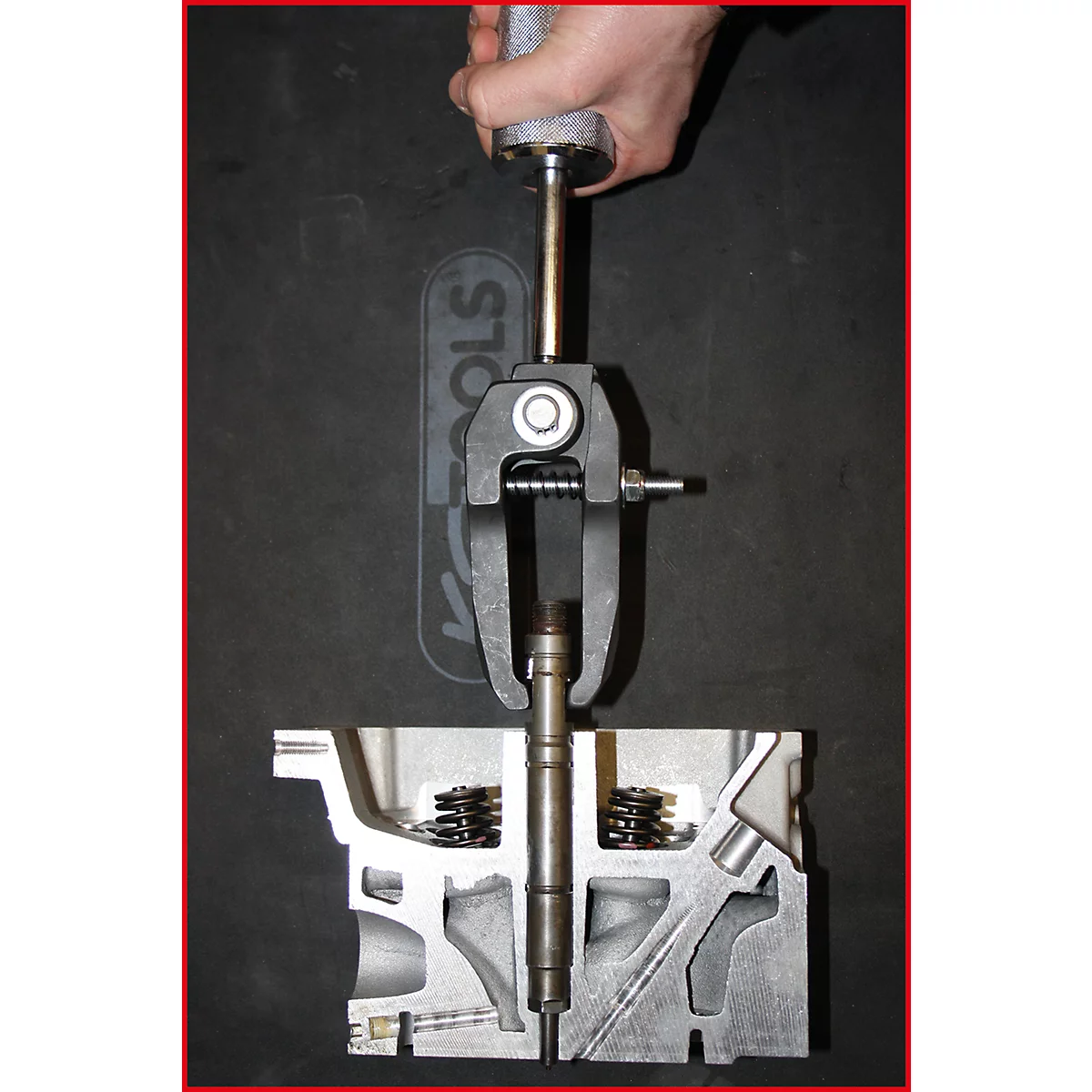 Ein Motor-Zylinderkopf mit Ventilwerkzeug. Das Werkzeug wird von einer Hand bedient.